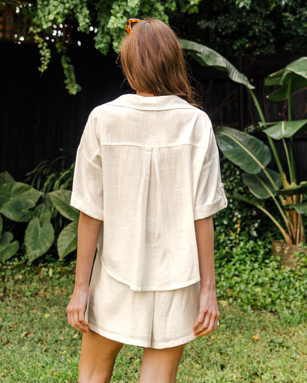 Person wearing a beige shirt and shorts set in a garden setting